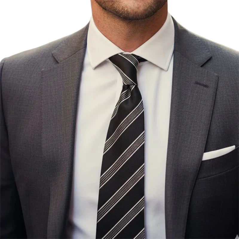 Man wearing a gray suit with a white shirt and black striped tie on a white background