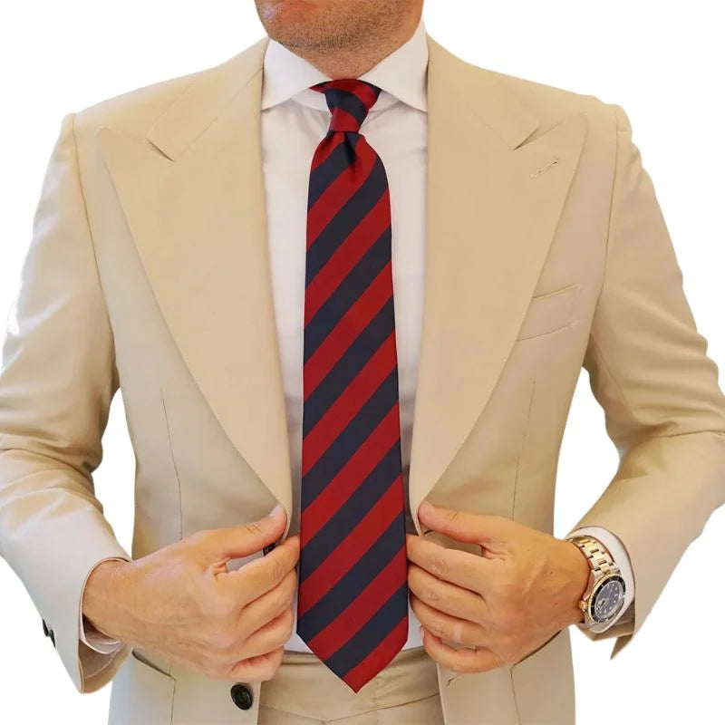 Man wearing a beige suit with a red and navy striped tie on a white background