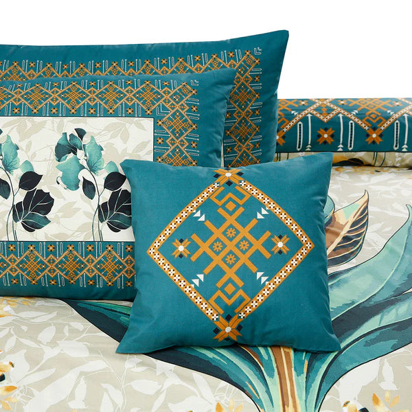 Teal decorative pillows with geometric patterns on a bedspread with floral and abstract designs.