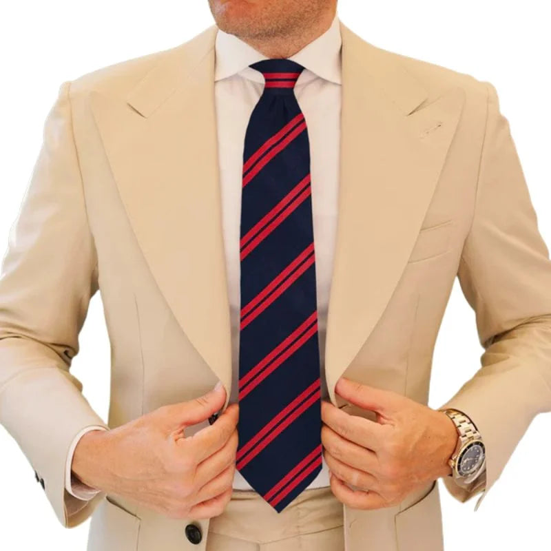 Man wearing a beige suit with a navy and red striped tie on a white background