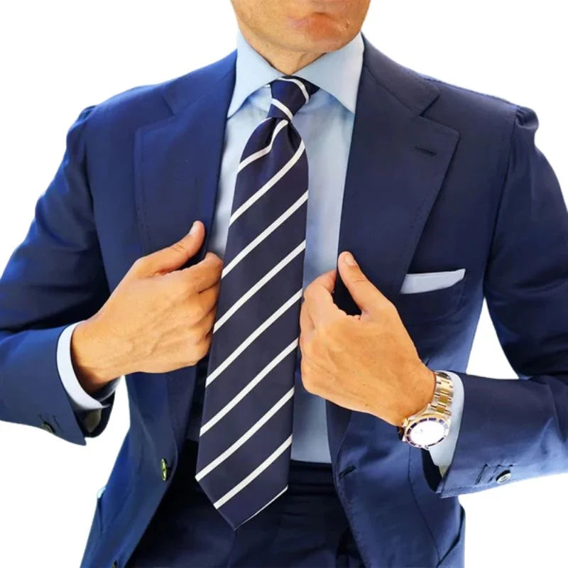 Man adjusting his blue suit jacket with a striped tie on a white background